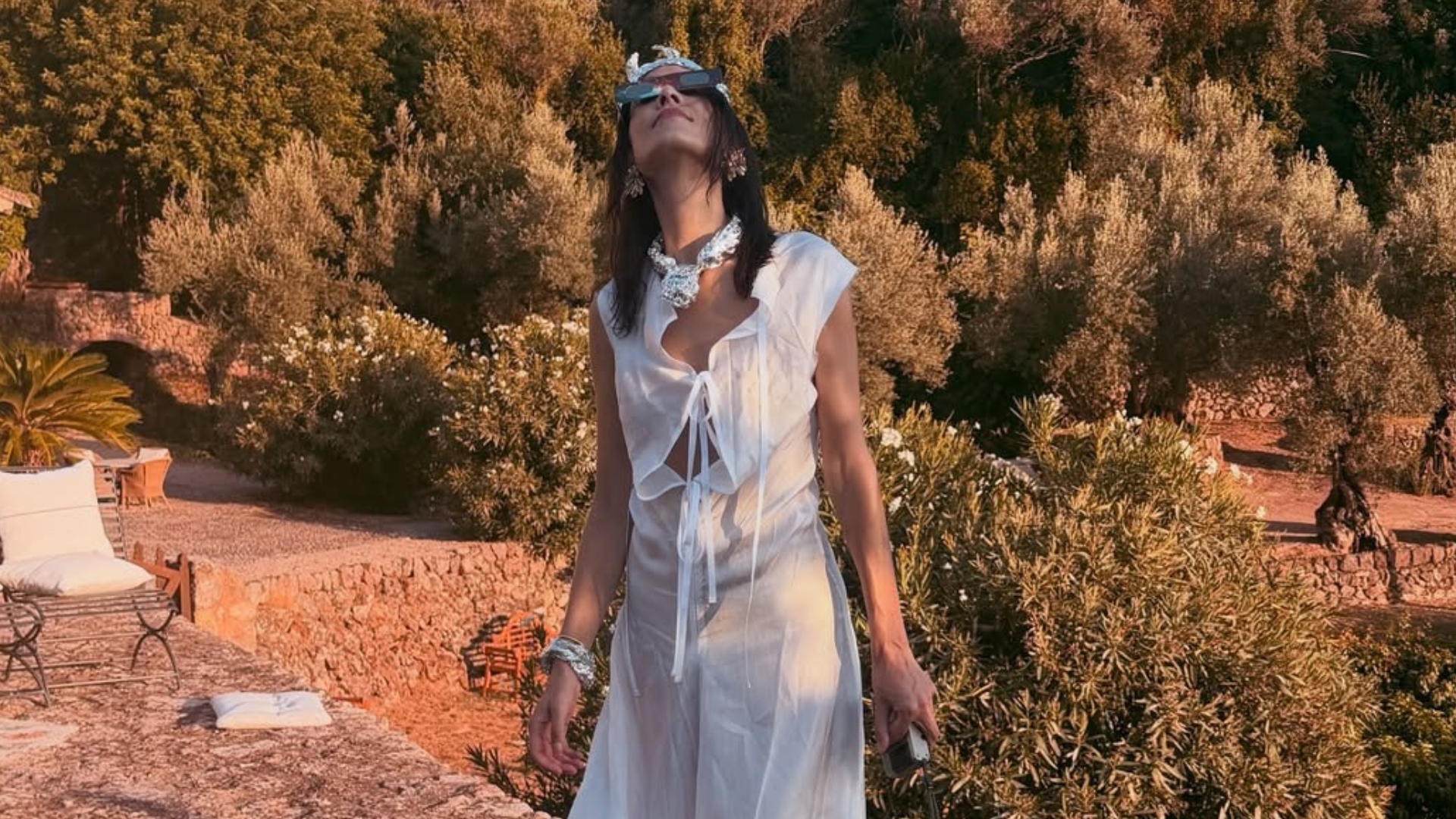 Alexa Chung wears transparent water shoes with a white cotton midi dress and sunglasses.