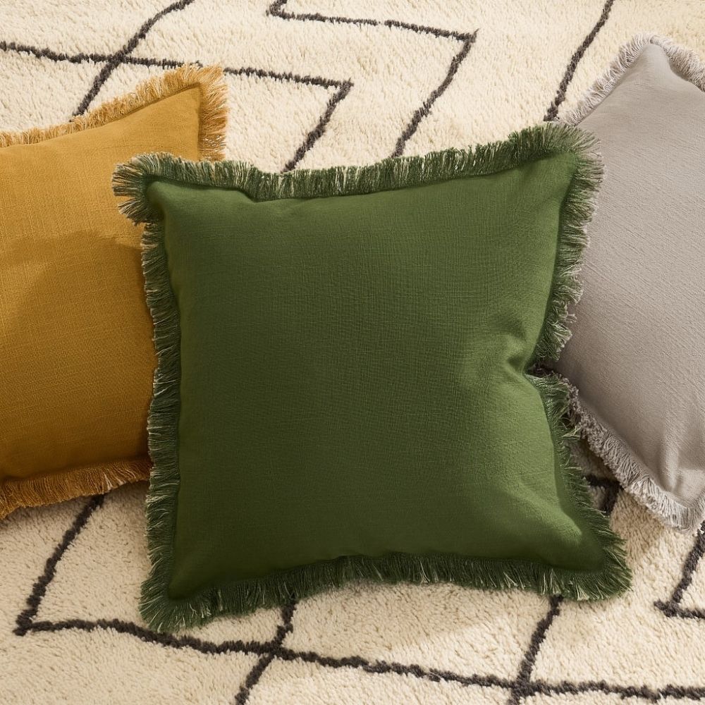 3 fringed cushions on top of white and black rug