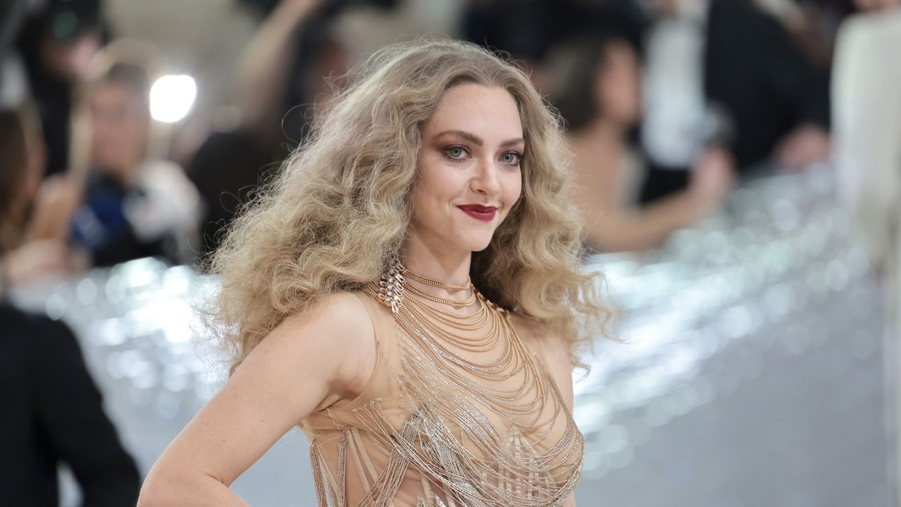 A blonde woman, Amanda Seyfried, with voluminous curly hair.