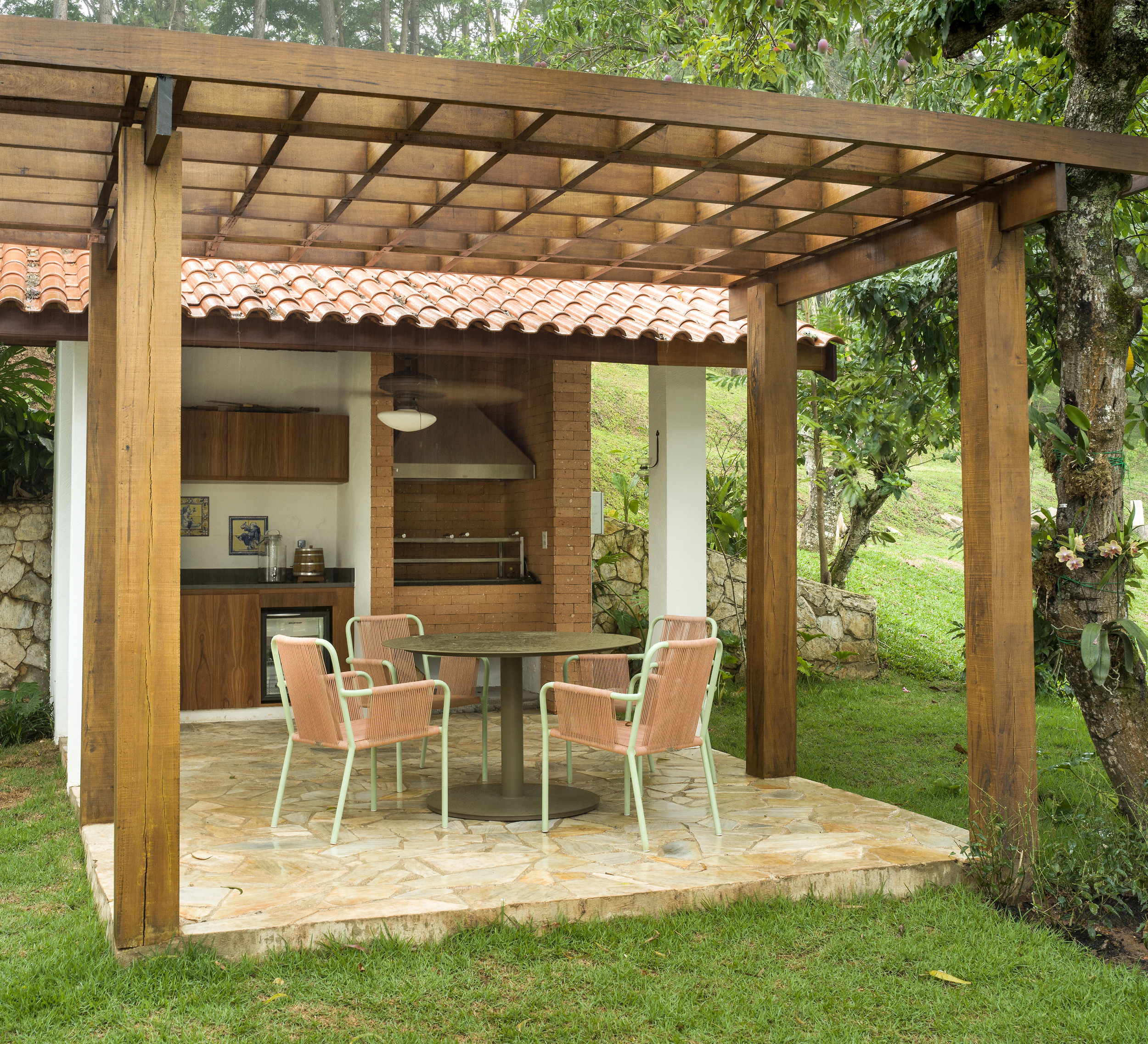 An outdoor kitchen with a wooden pergola, and stone fireplace