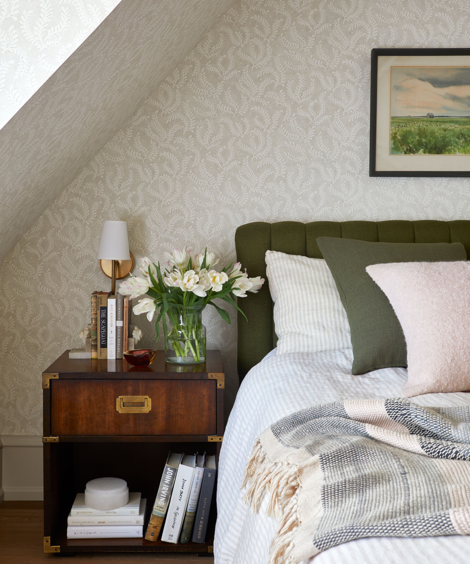 bedroom with light gray fern wallpaper, wooden nightstand, and bed with dark green headboard