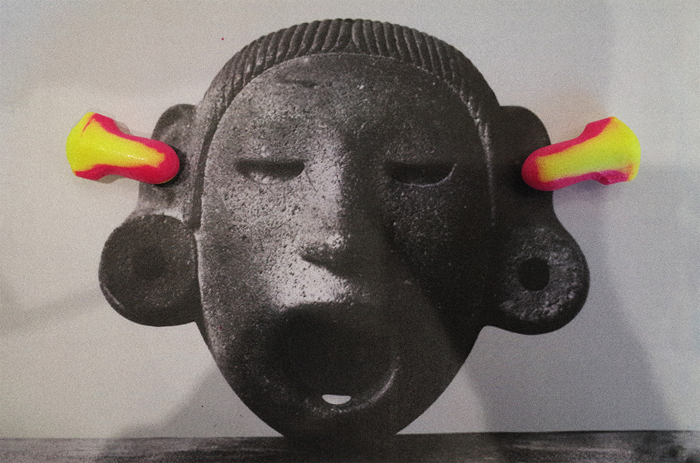Black and white picture of a stone mask with red and yellow earplugs