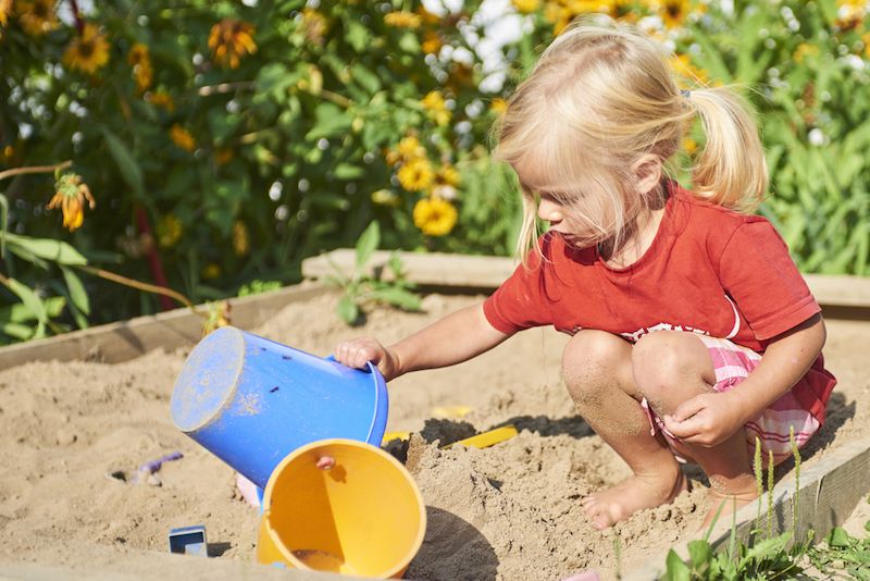 A little girl plays in a sandbox.