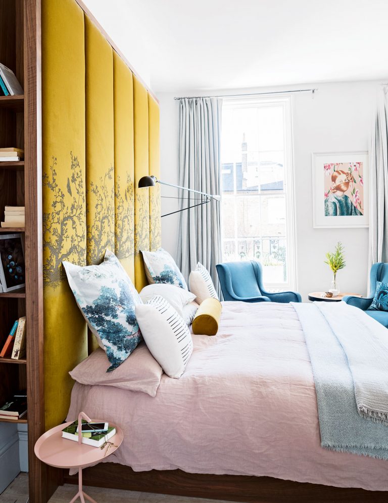 blue and yellow bedroom with pink bedding and large headboard