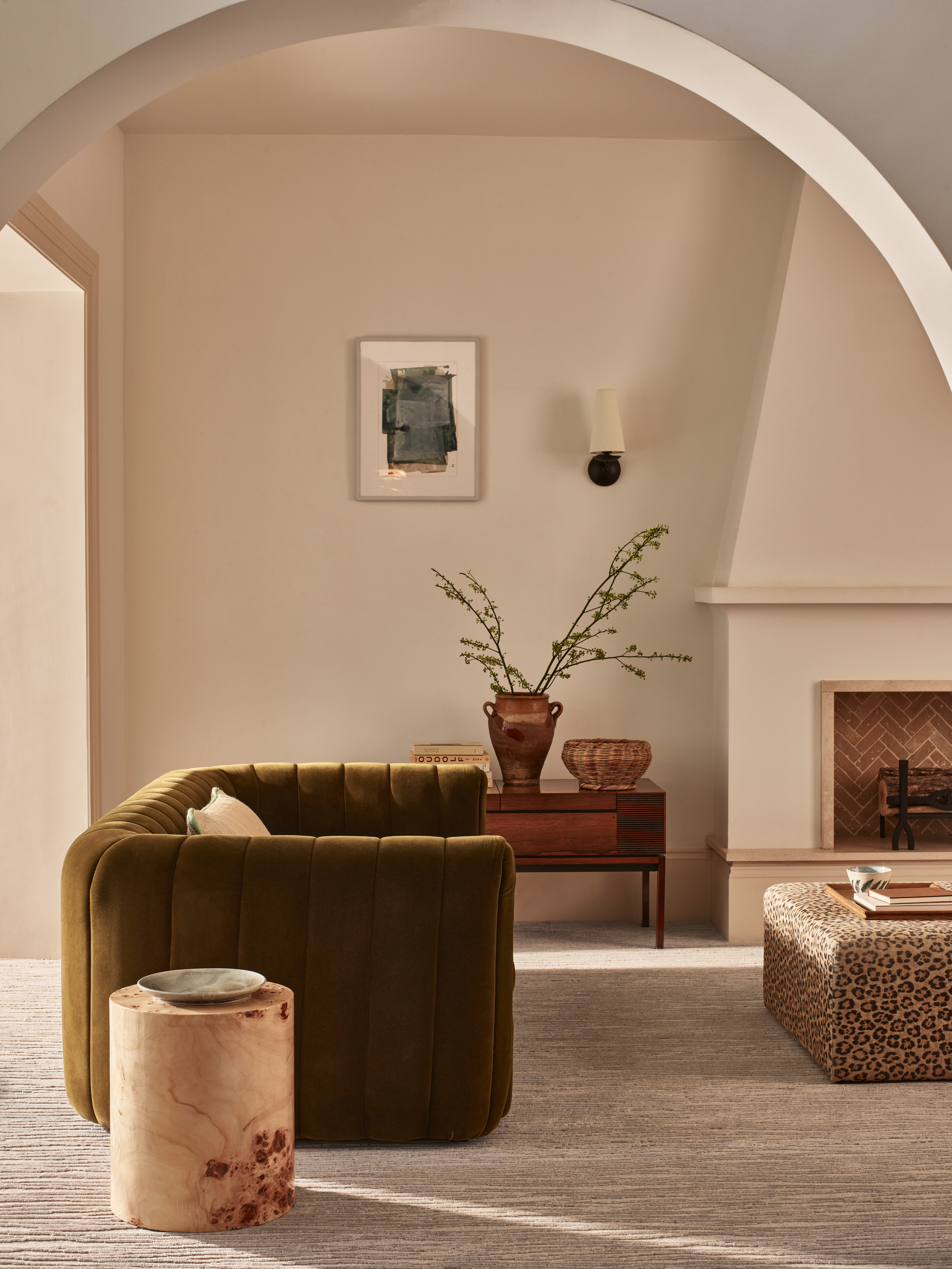 A living room with a textured taupe carpet, a green fluted sofa, and a sloped fireplace