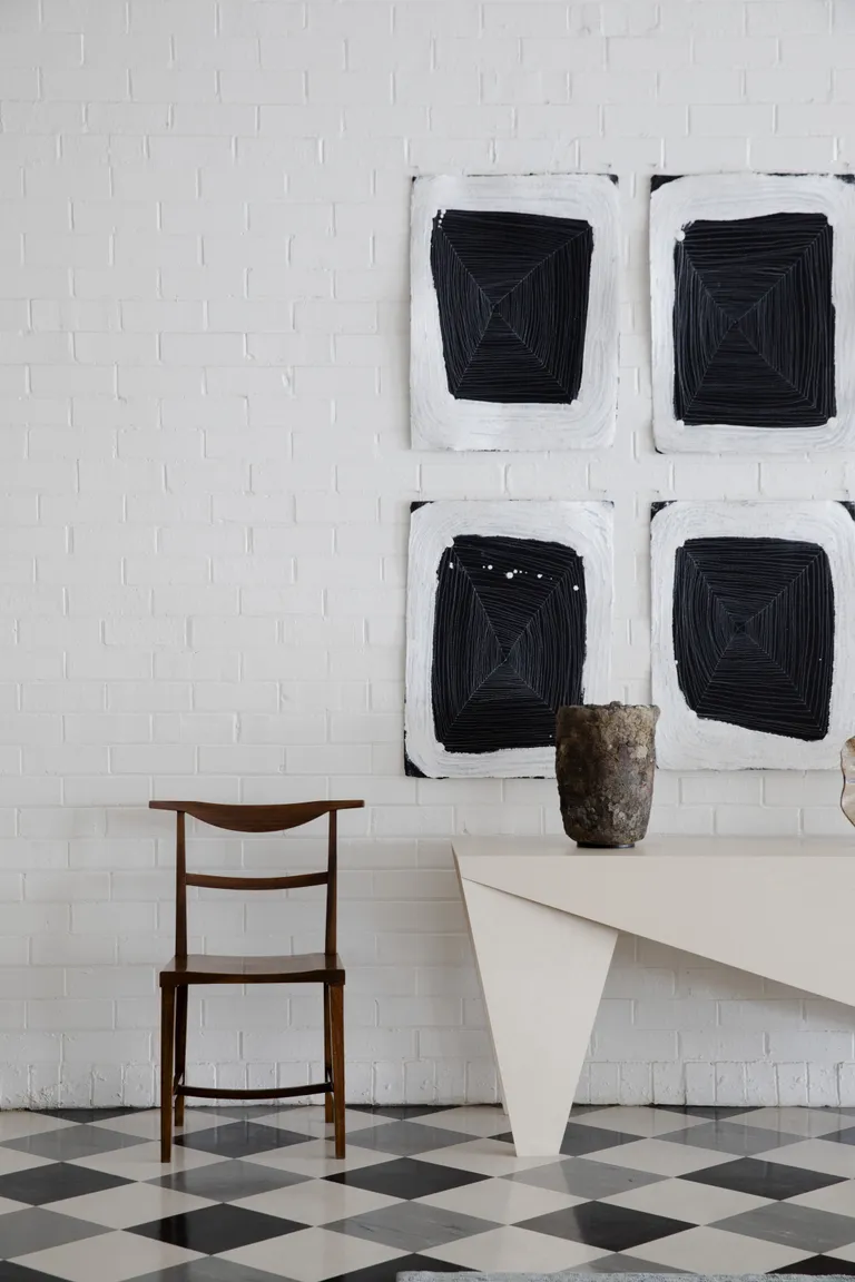 white living room with checkerboard floor and art on the walls