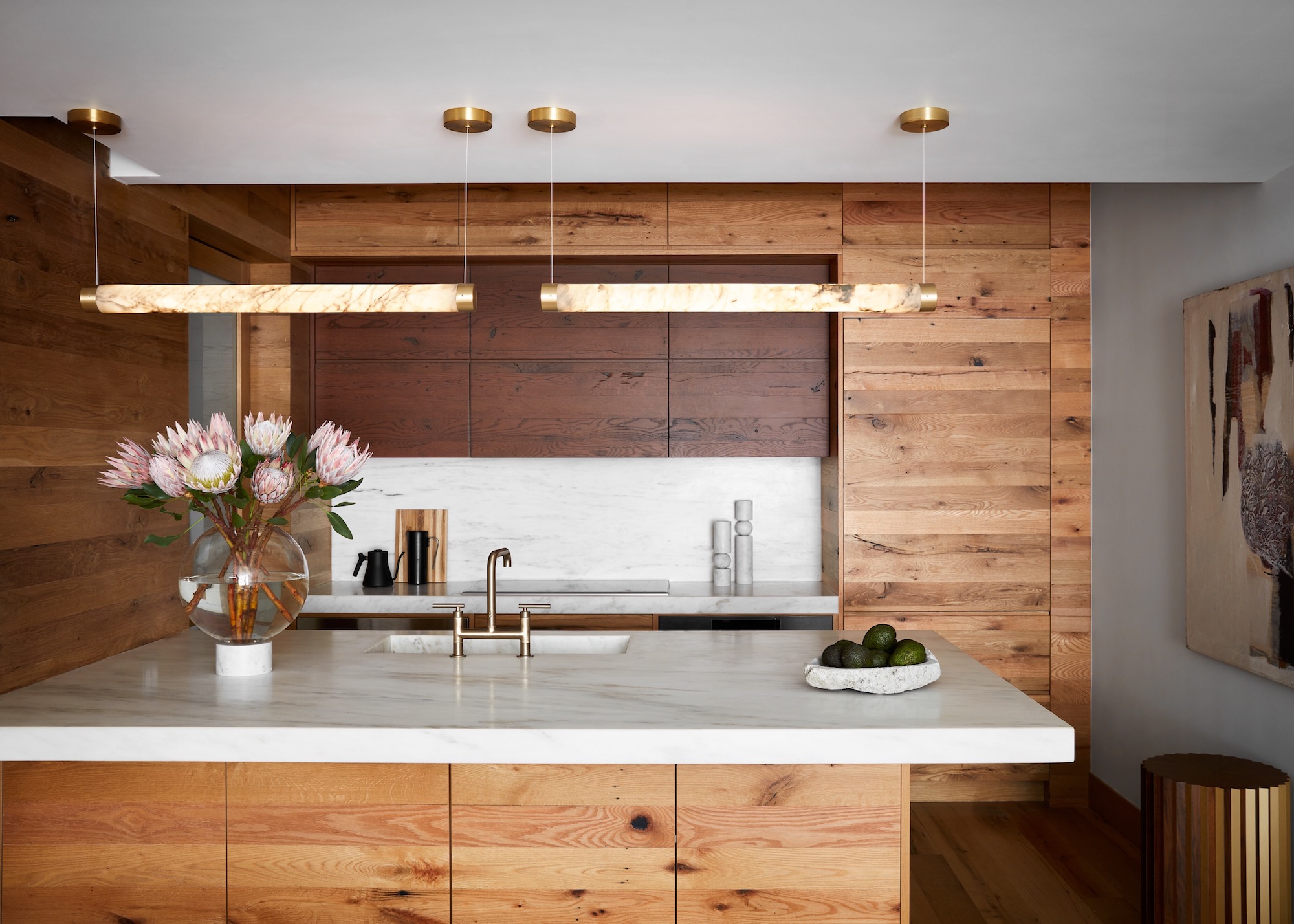 wood kitchen with marble worktops and horizontal lighting pendants