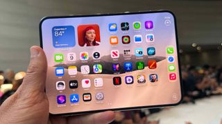 iPhone Duo opened and being held up by a single hand at a tech showcase.