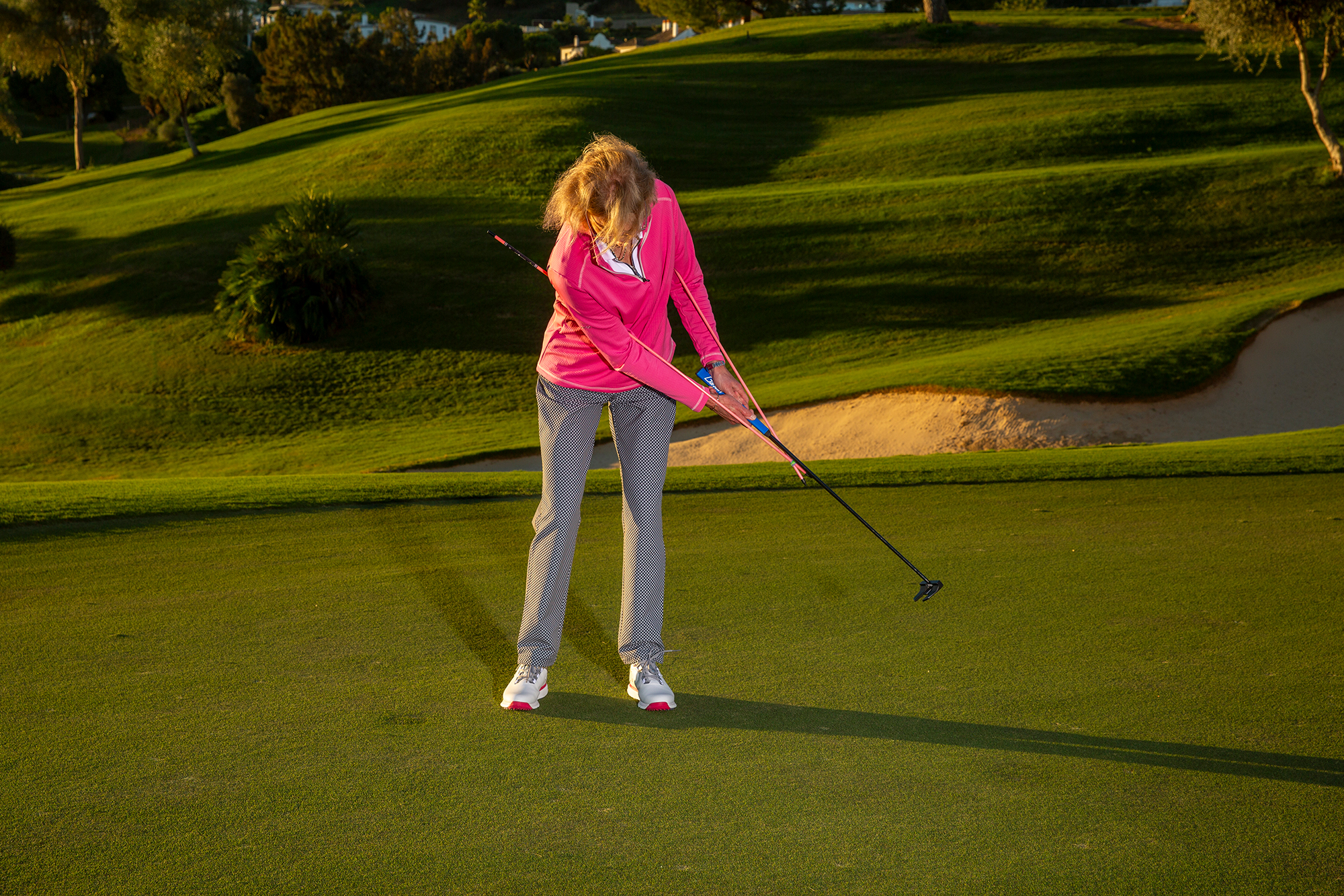 Sarah Bennett using two alignment sticks under her arms to maintain connection in the stroke as part of a putting drill