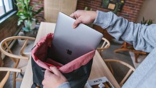 back to school deals - student sliding MacBook into Hershel backpack laptop sleeve