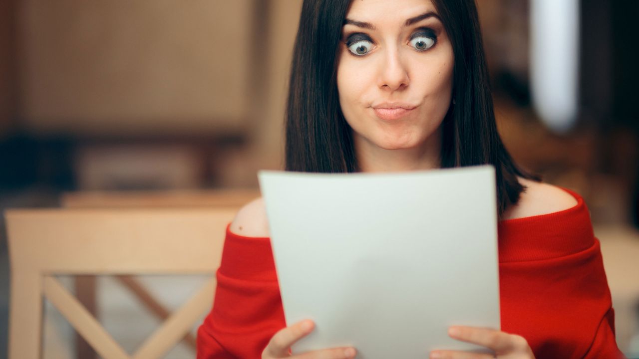 A woman reads through some papers with a incredulous look on her face.