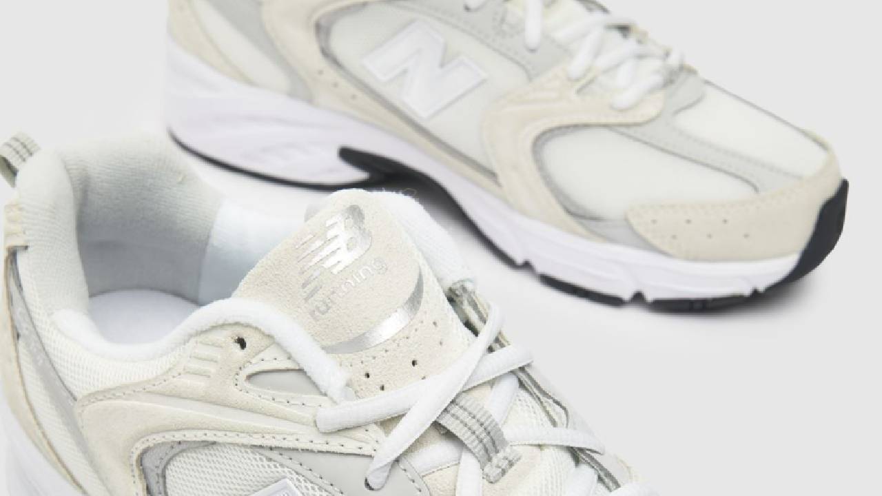 A pair of cream and silver New Balance trainers available from Schuh.