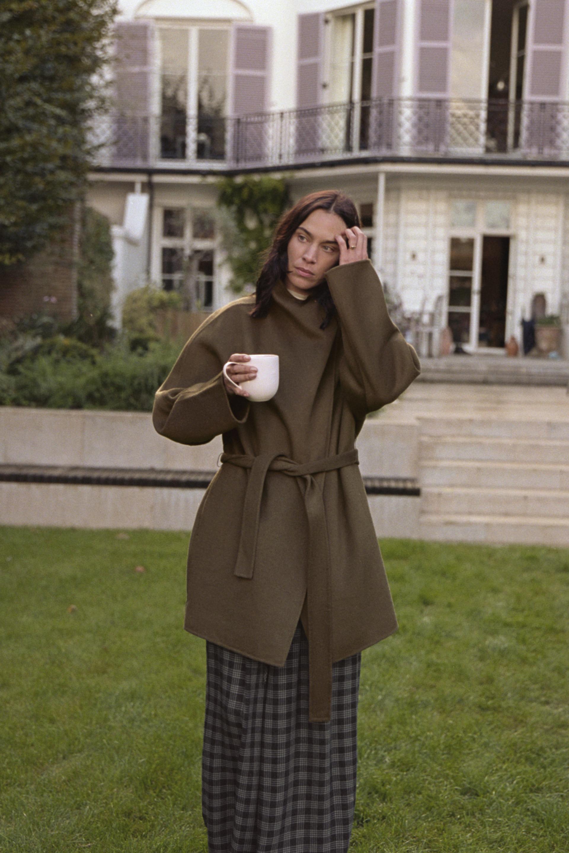 Model wears Zara winter coat trends. She wears a olive funnel necked coat.