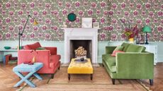 colourful sofas against a purple flowery wallpaper in living room with fireplace and wood floors