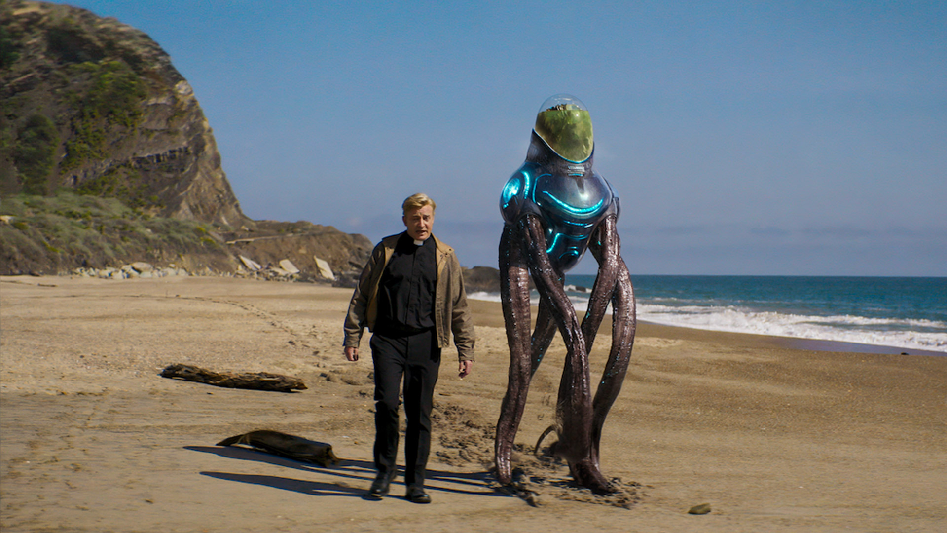 A priest walks down the beach with an alien with tentacles