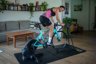 A woman rides on Rouvy using a Bianchi bike mounted to an Elite indoor trainer