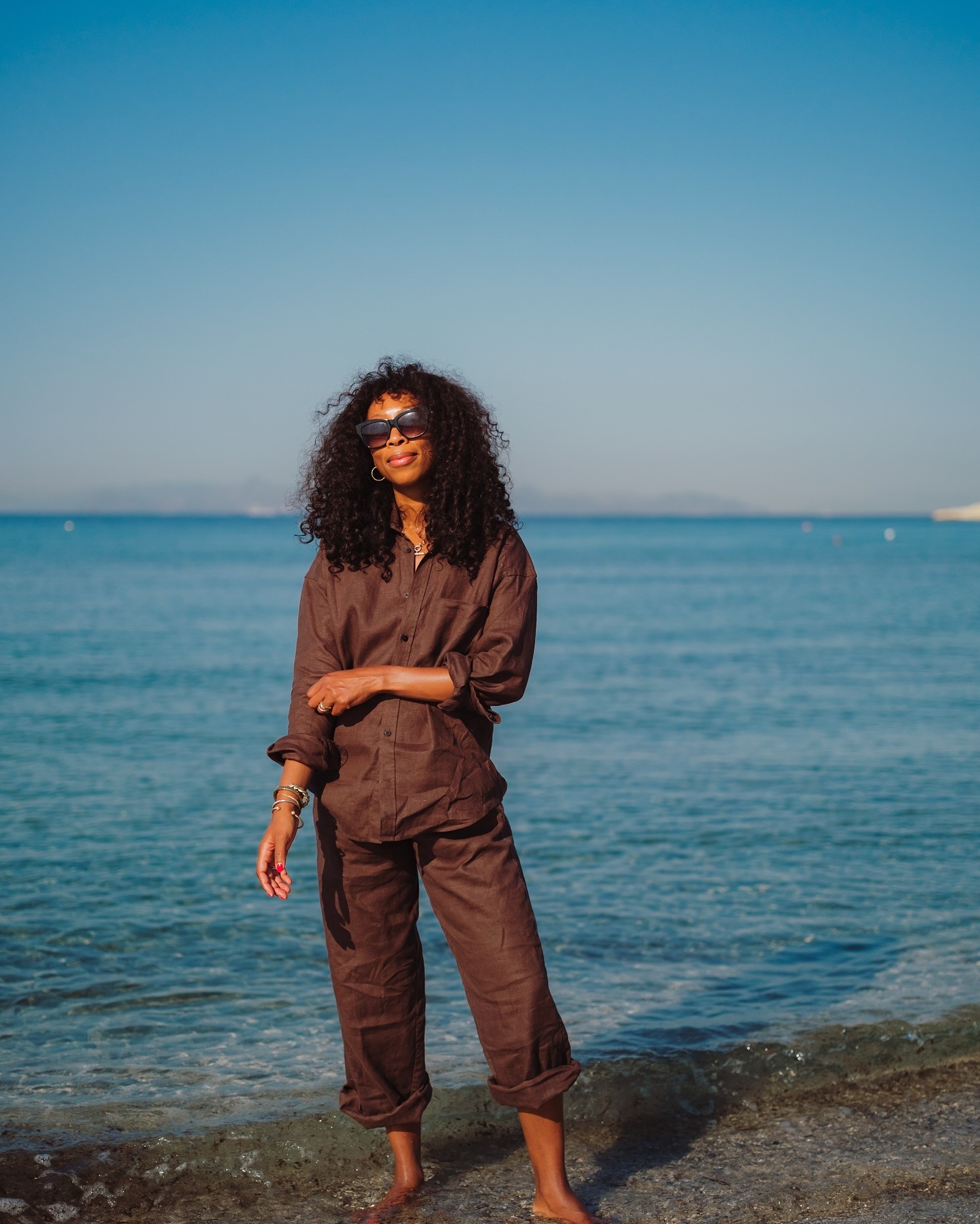 The woman is wearing a brown linen shirt and brown linen pants