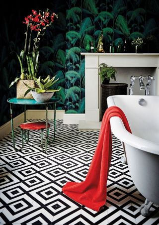 bathroom with monochrome patterned flooring, pattern clashing wallpaper, a freestanding bath and small side table with house plants a great example of how to mix pattern and prints in interiors by carpetright