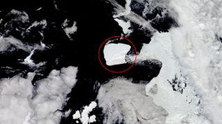 A large iceberg in the ocean surrounded by clouds