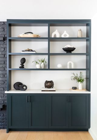 Gray open hutch with curated, minimal display of ceramic ornaments and plants