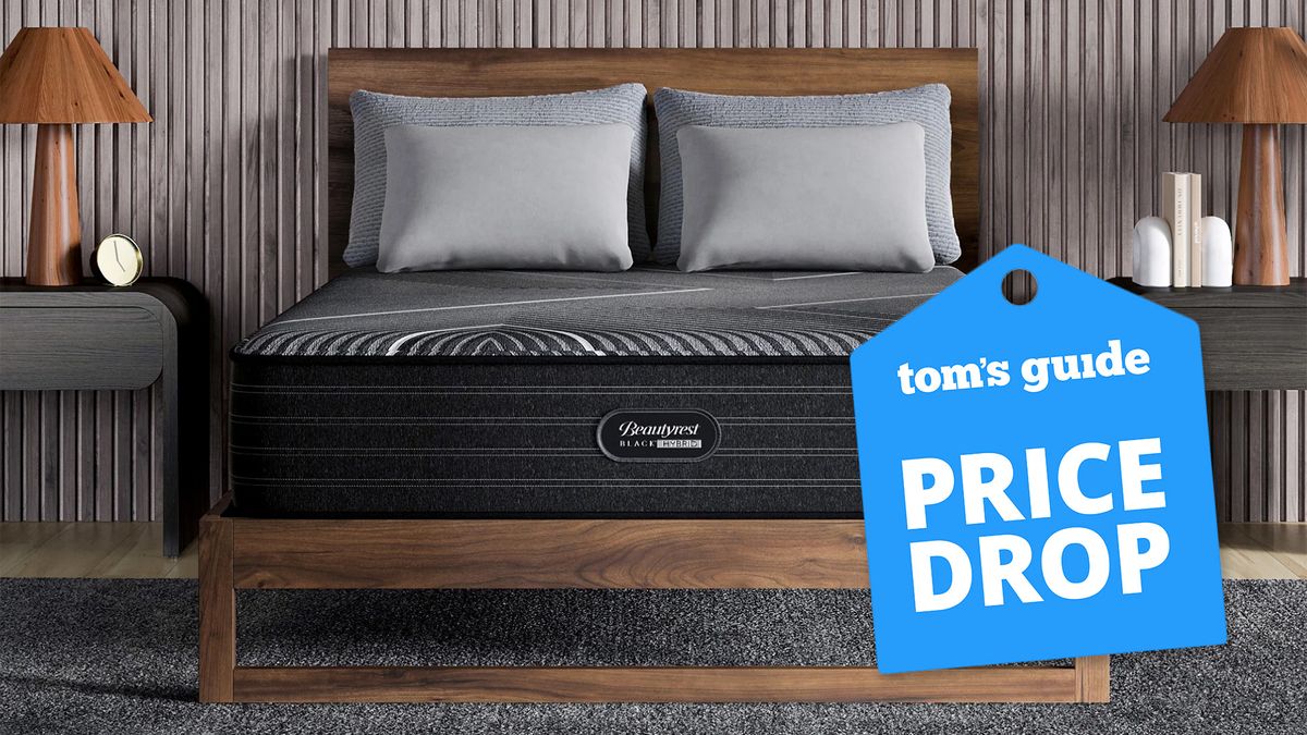 The Beautyrest Black Hybrid mattress on a wooden bed frame in a bedroom, a Tom&#039;s Guide price drop deals graphic to the right