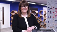 Julie Harrison, chief commercial officer (CCO) of Brother UK, pictured in an open plan office space leaning against a Brother printer.