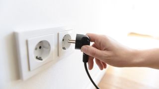 Hand holding plug near socket