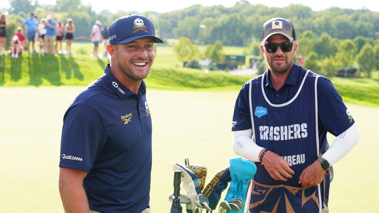 Bryson DeChambeau smiles next to his caddie