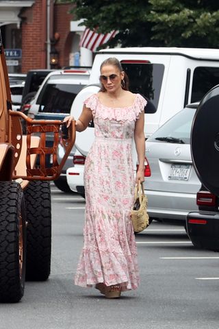Jennifer Lopez gets into a car in the Hamptons wearing a pair of wedge sandals with a pink floral dress and a basket bag