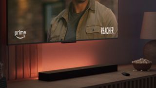 The Amazon Fire TV Soundbar Plus underneath a TV showing Reacher.