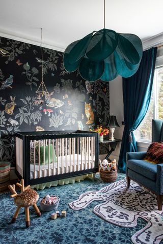 boy nursery with lots of pattern, bold wallpaper, black crib, blue patterned floor, blue armchair, blue drapes, mobile, black side table, toys, basket