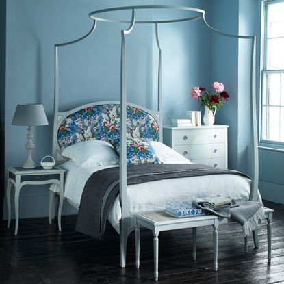 bedroom with four poster bed cushions and wooden flooring