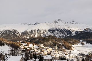 An aerial view of St Moritz with fresh snow, photographed from the sky during the day with snowy mountains in the background