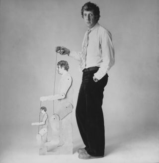 Portrait of theatre director Jonathan Miller holding the strings of two marionettes in his own likeness, circa 1975. (Photo by Radio Times/Getty Images)