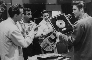 Elvis Presley showing framed gold to (L-R) drummer D.J. Fontana, singer Gordon Stoker and guitarist Scotty Moore