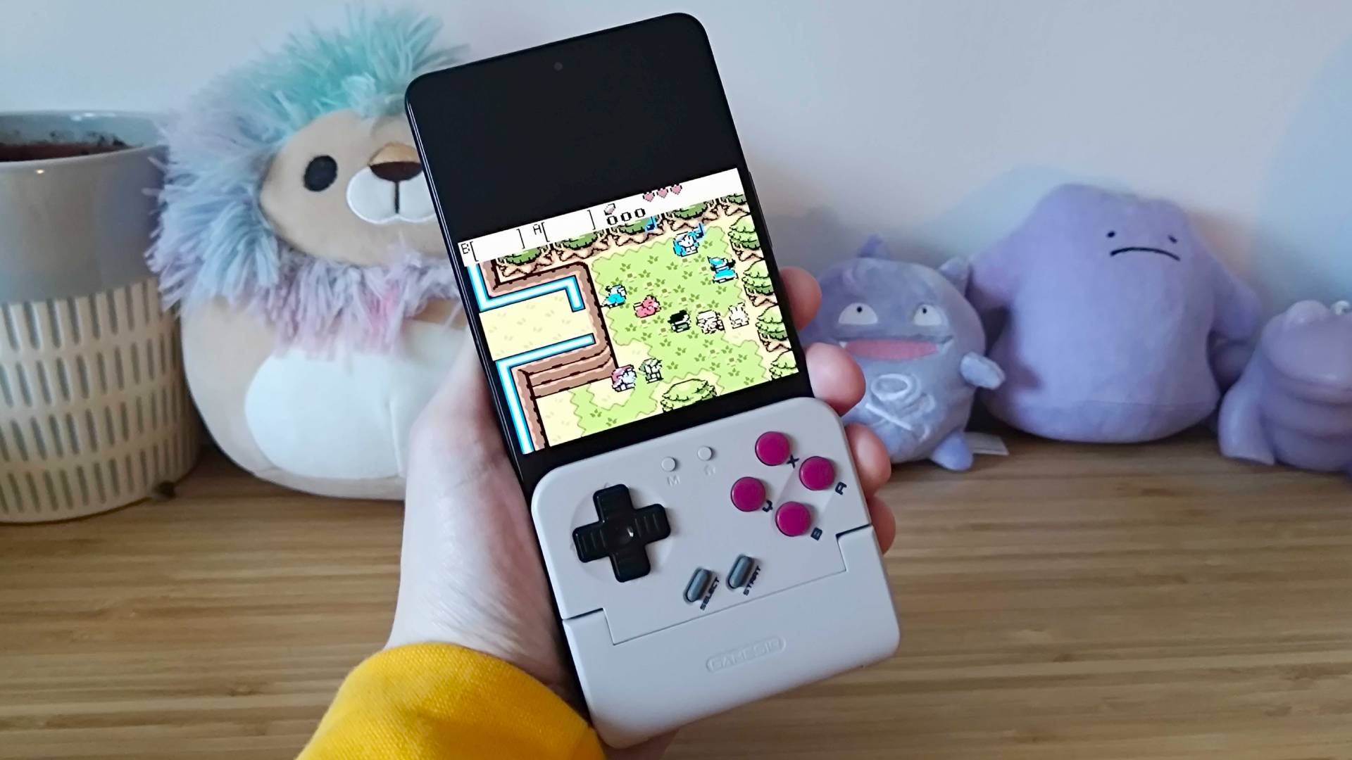 Hand holding Gamesir Pocket Taco attached to Asus ROG Phone 9 Pro with Zelda Oracle of Ages gameplay on screen.