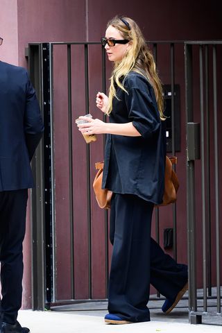 Jennifer Lawrence wearing a button-down shirt, loose pants, and flat shoes