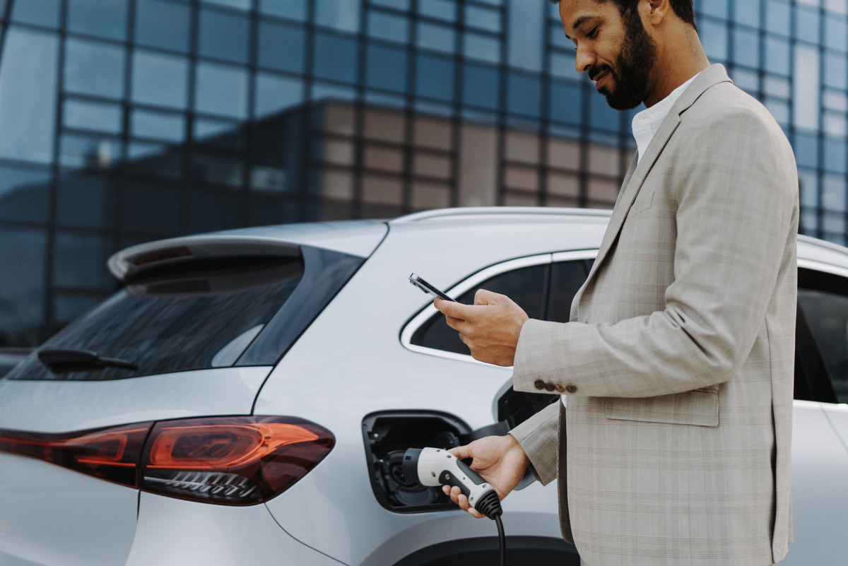 A person using their phone while charging their electric car