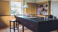 yellow kitchen with brown painted freestanding kitchen island in a classic english kitchen