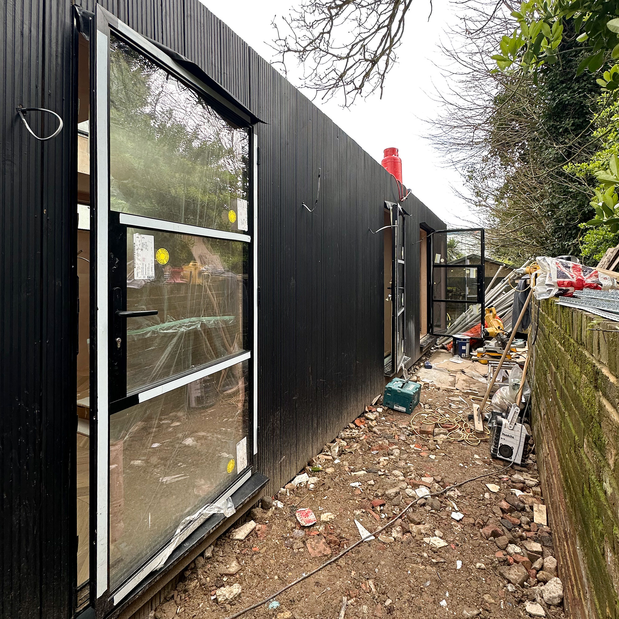 Summerhouse mid-renovation, showing rubble in between building and garden wall