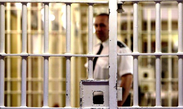 A prison guard viewed through cell bars.