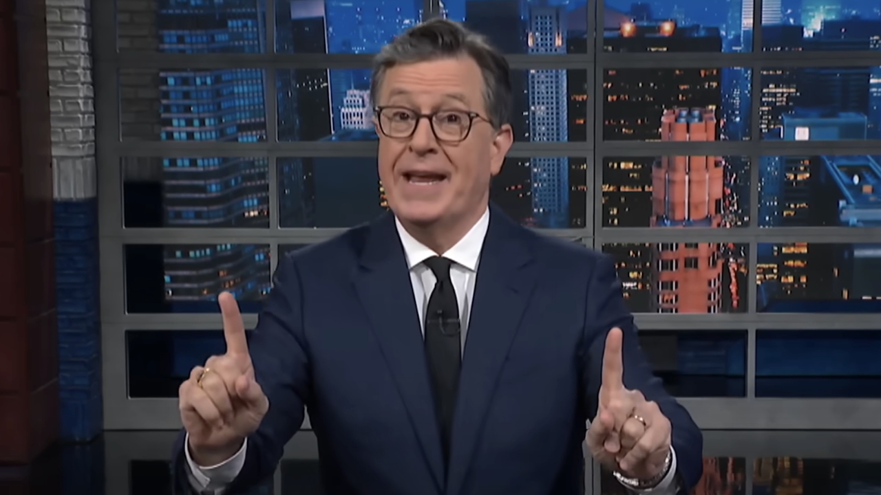Stephen Colbert pointing up with both index fingers while giving monologue on The Late Show