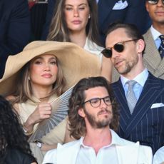 Jennifer Lopez attends Wimbledon on July 12, 2026 wearing a massive raffia hat and a dress from Ralph Lauren, joining Tom Hiddleston who wears a navy pinstripe suit