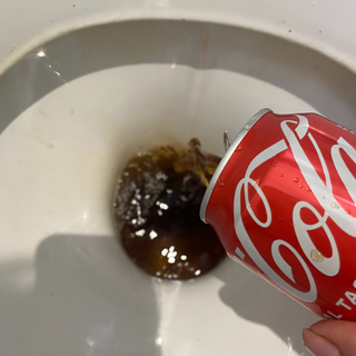 Pouring a can of coke into a toilet.