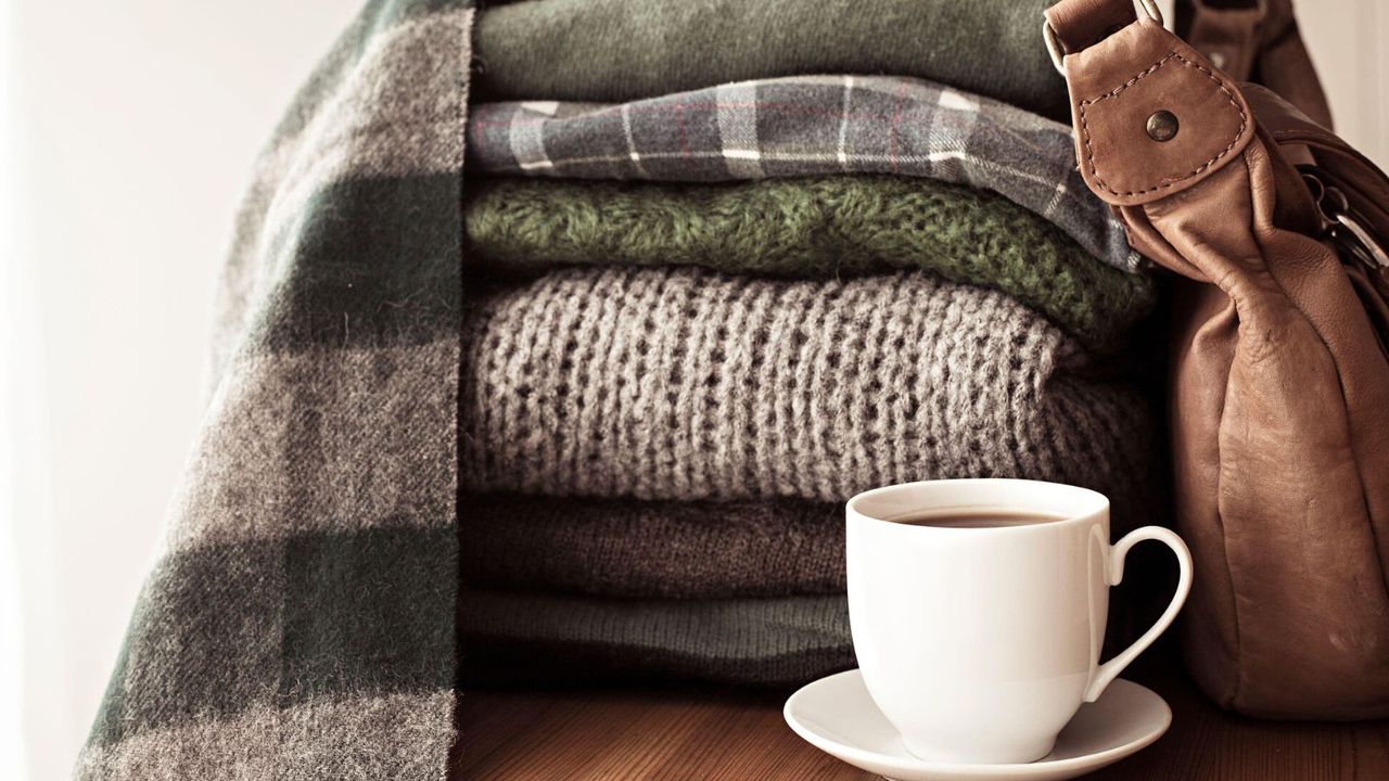 A pile of folded clothes next to a coffee cup 