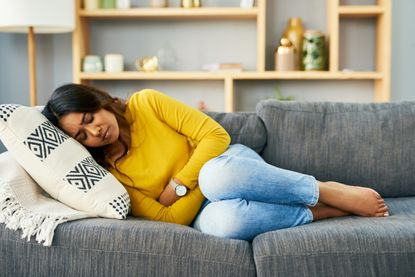 Woman suffering with period cramps at home