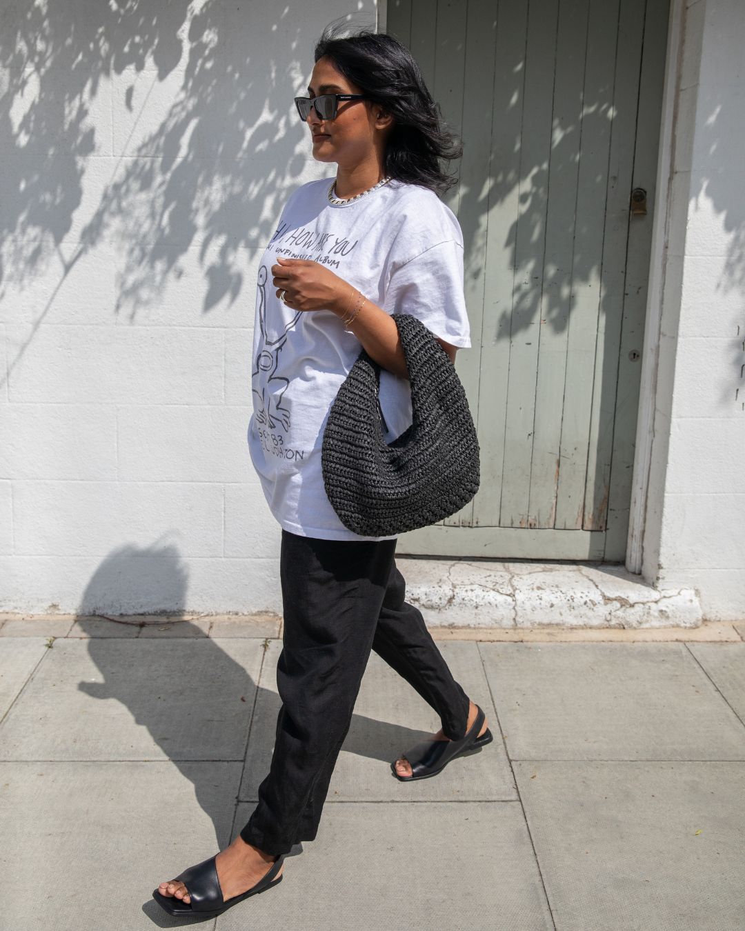 @chiarasatelier wears H&M black linen trousers with a white t-shirt, black sandals and black raffia tote