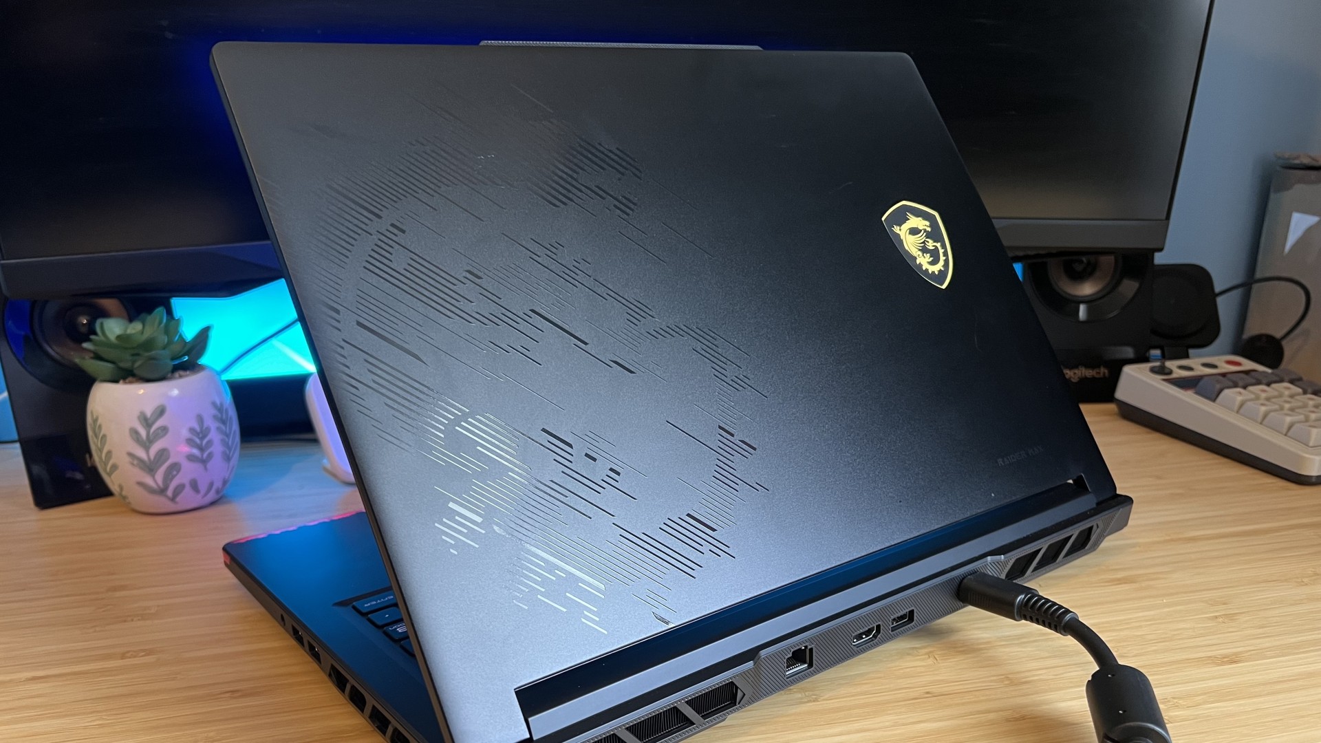 Back lid on MSI Raider 16 Max with laptop turned away on a wooden desk