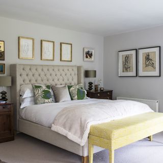 bedroom with white wall and picture farme and bedding with cushions and throw and rug