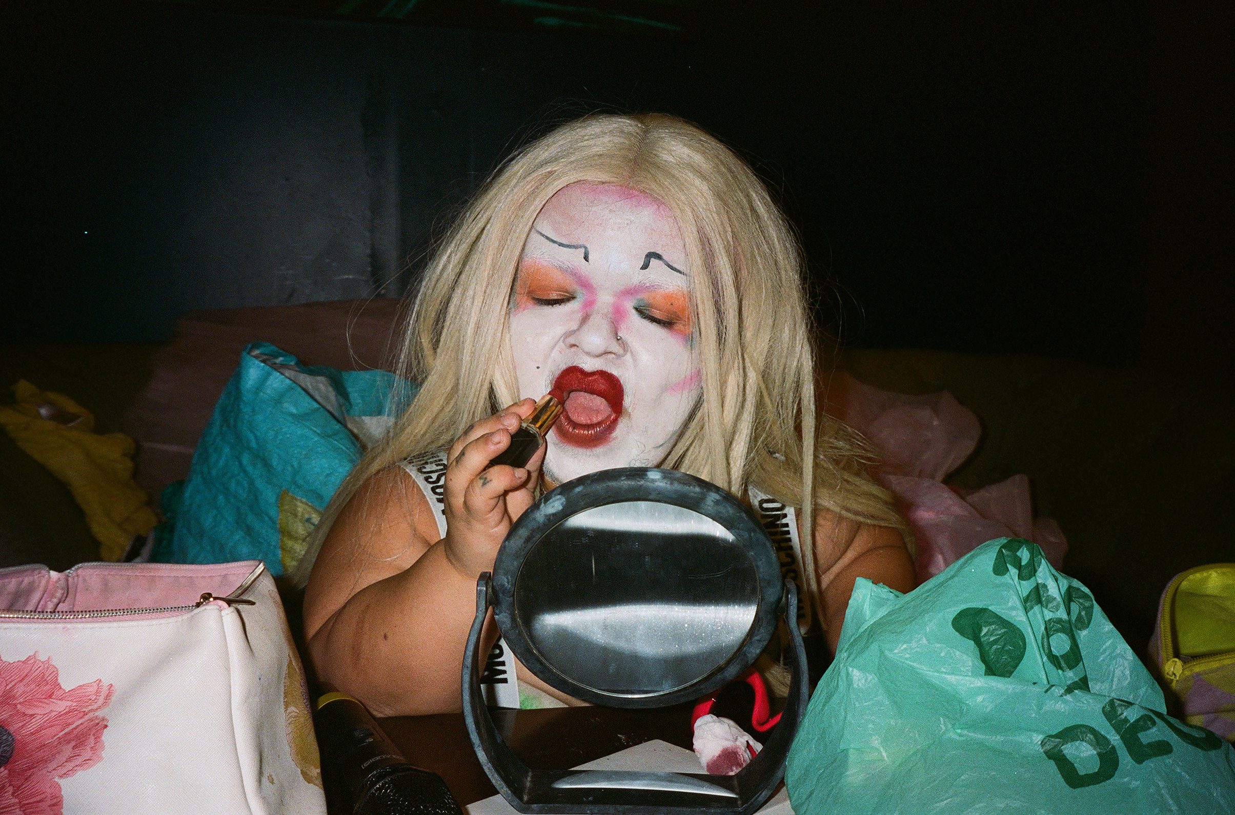 Colour photograph of a person applying lipstick in a small mirror
